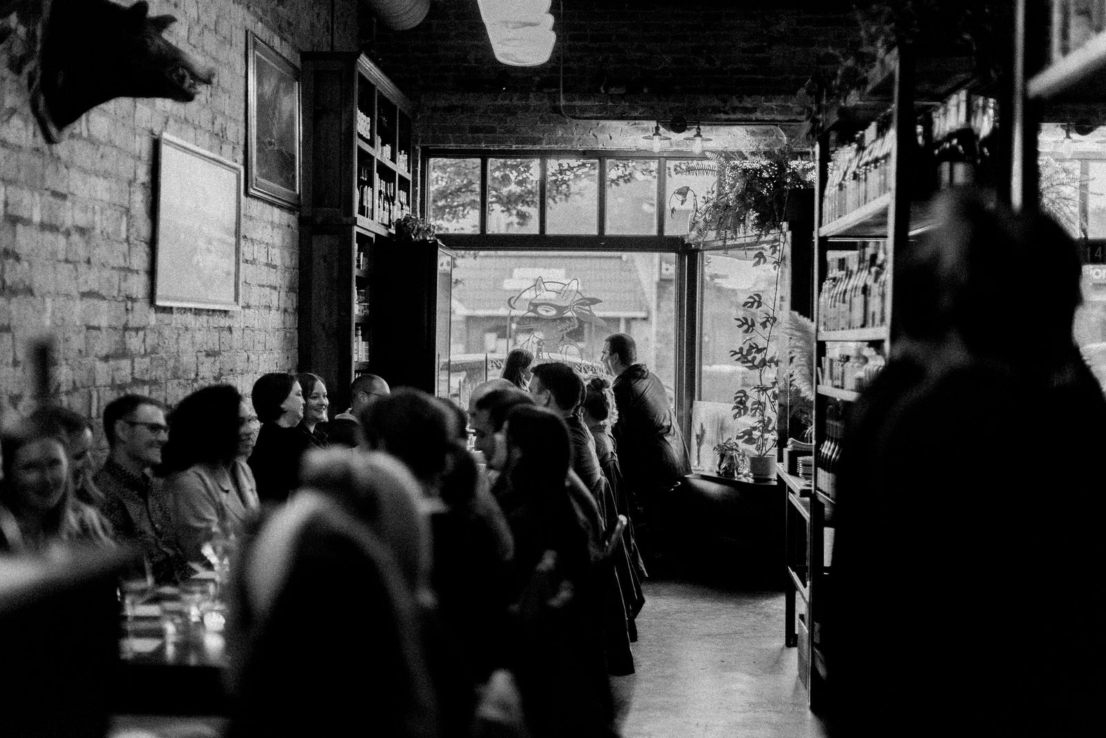 A full room at Field during a private party, the long table running toward the front windows